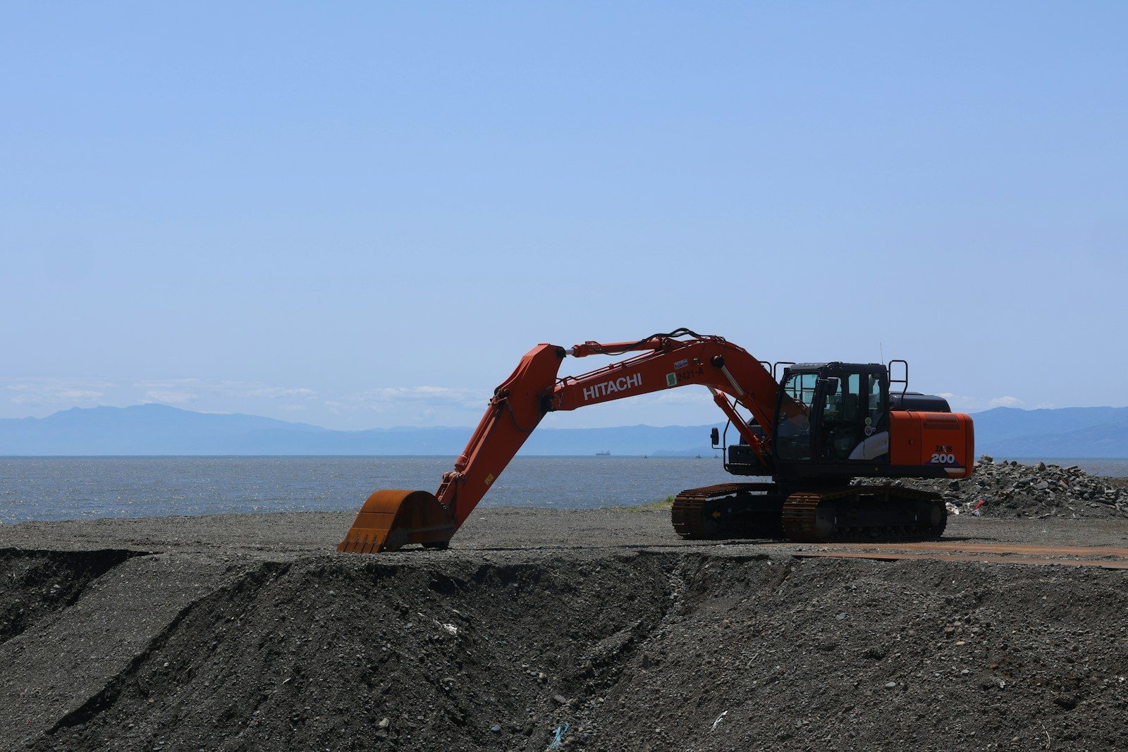 An excavator works by the water.